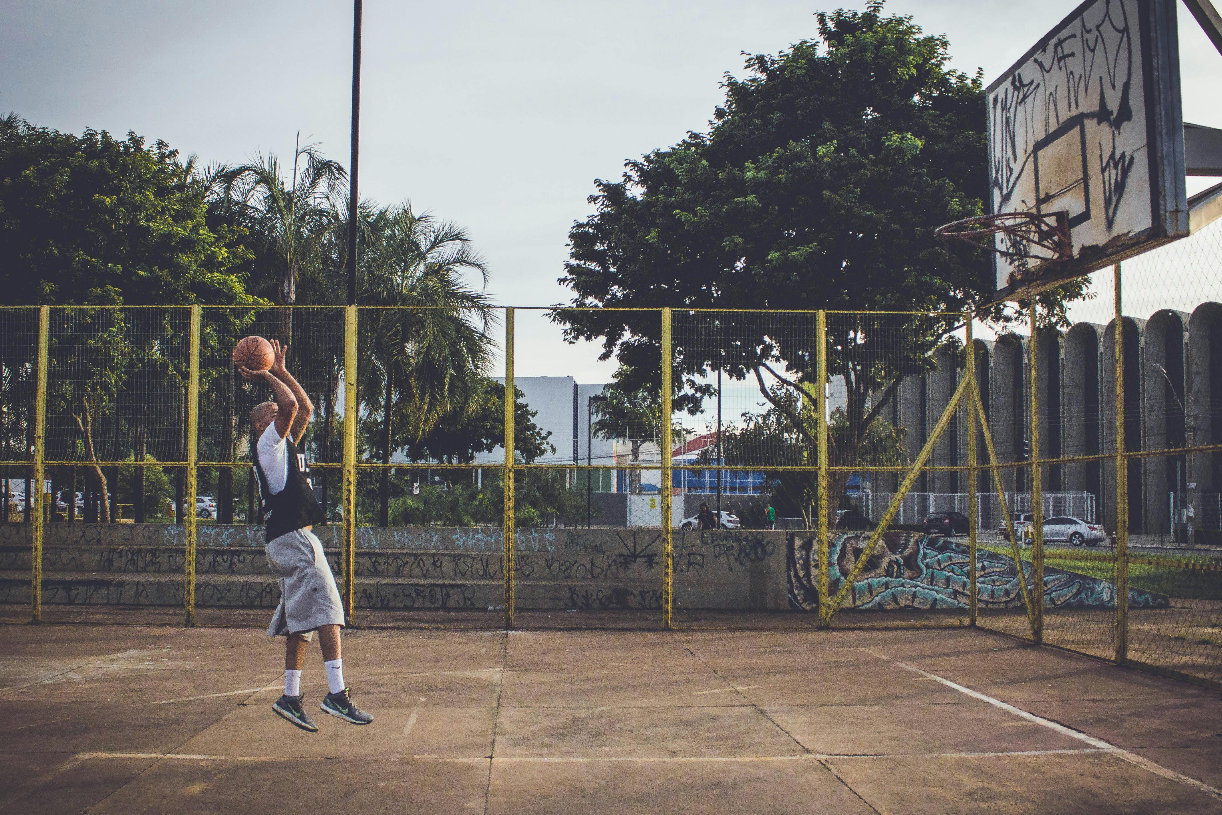 Persona de tez oscuras lanzando una pelota de baloncesto a la canasta